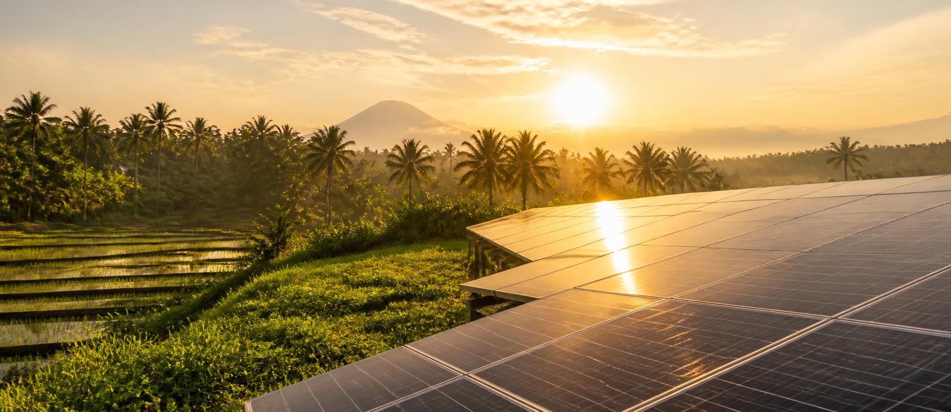 Solar panel array at sunrise in a rural Southeast Asian valley